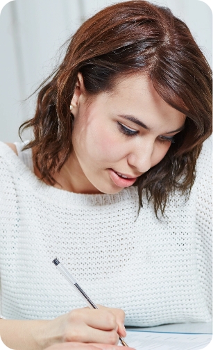 Nundah General and Emergency Dental Young woman in a white sweater writing on paper while looking down.