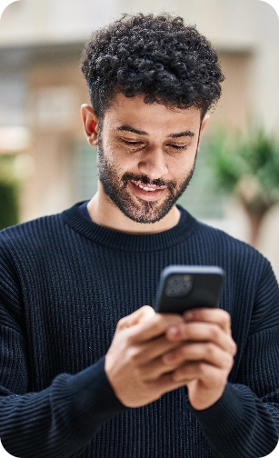 Nundah General and Emergency Dental Smiling man looking at his phone in an outdoor setting.